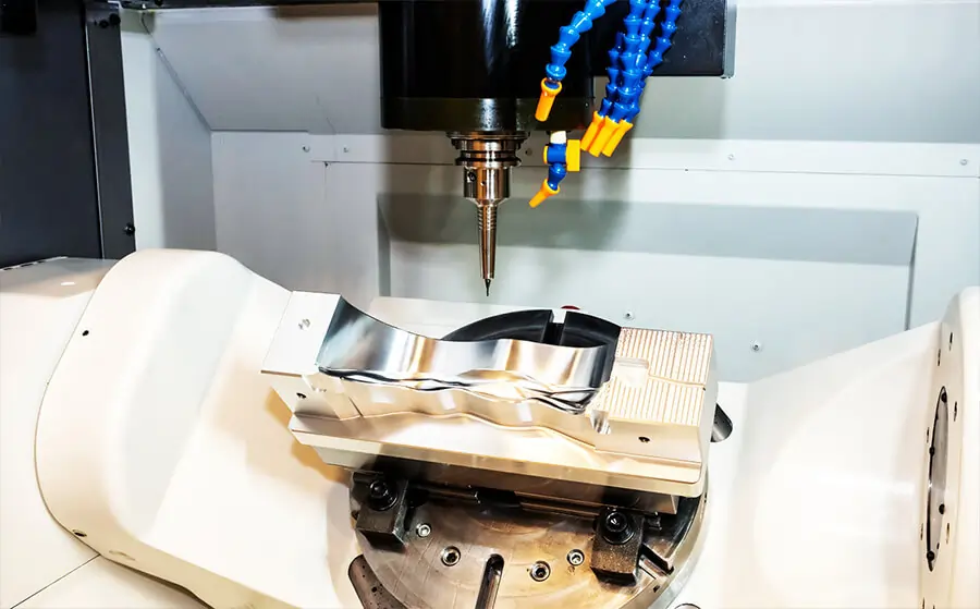 5-axis CNC machine milling a complex aluminum part with precision tooling and coolant nozzles in operation.