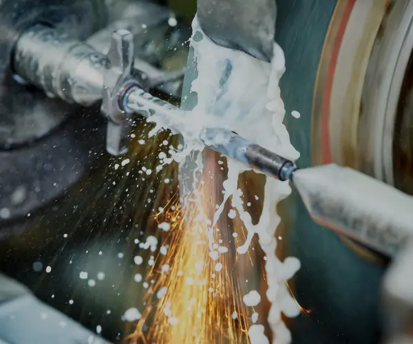 CNC grinding process with coolant and sparks for precision metal part finishing