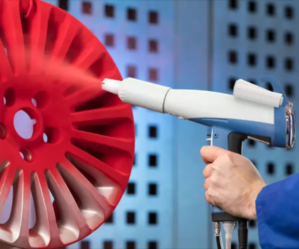 Electrostatic spray painting a red component for even coating on MJF printed parts.